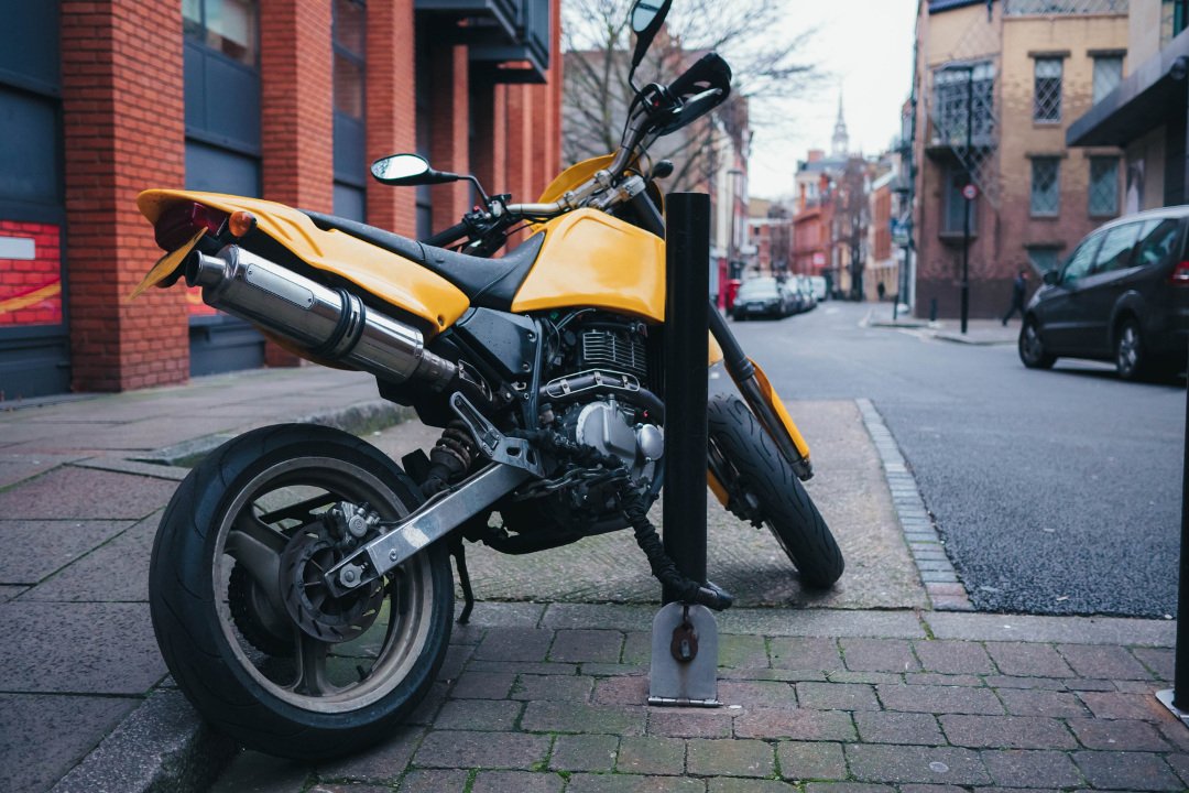 A motorcycle on the street chained to the pole