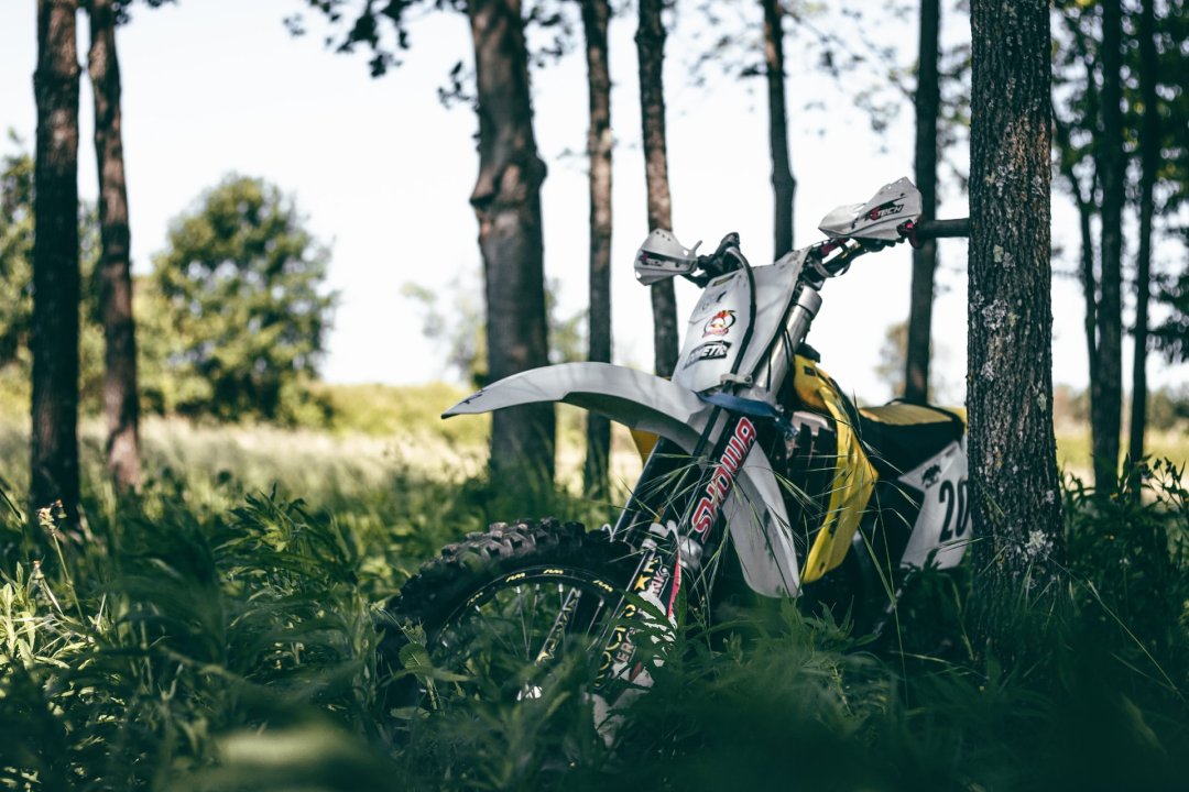 Moto cross appuyée contre un arbre dans un sous-bois