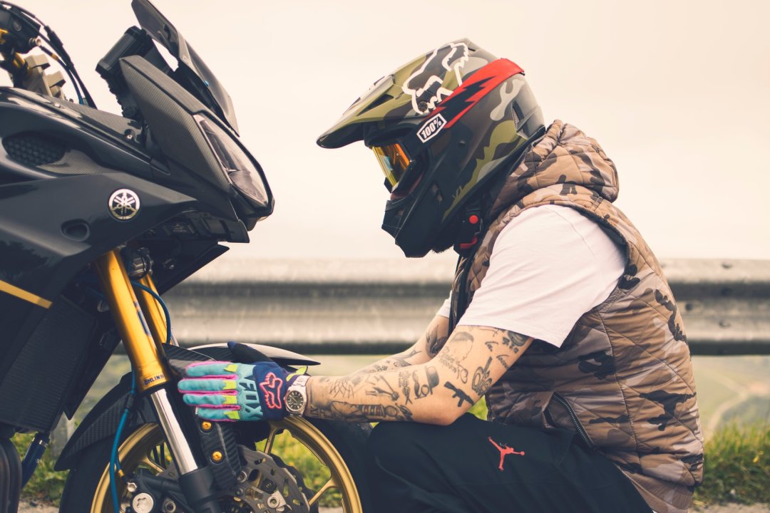 Homme accroupi devant une moto Yamaha de couleur grise - moto japonaise