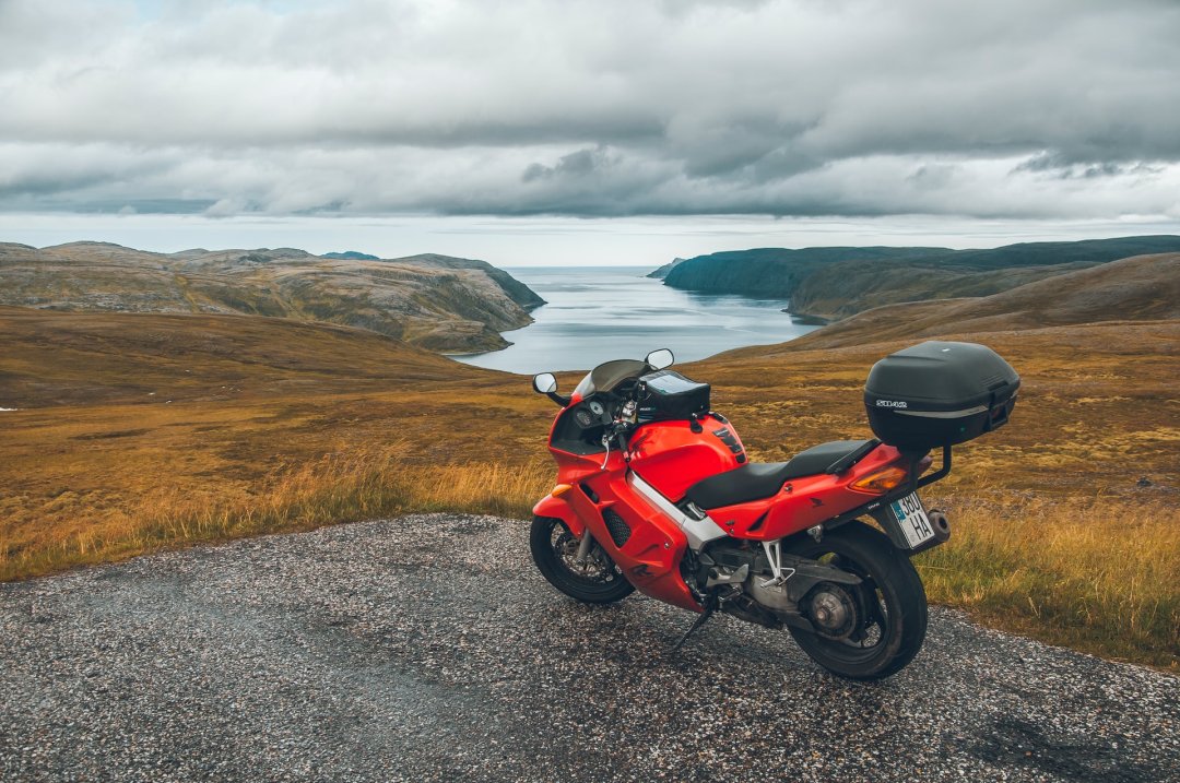 Moto routière de couleur rouge garée face à un paysage naturel