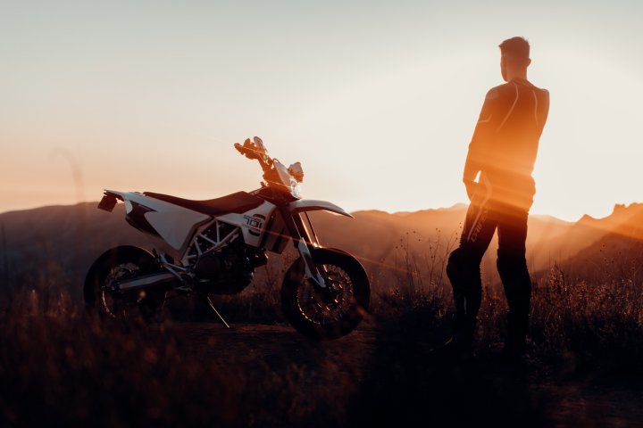 Homme se tenant debout à côté d’une moto supermotard