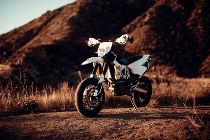 Moto supermotard de couleur blanche garée sur une piste de terre