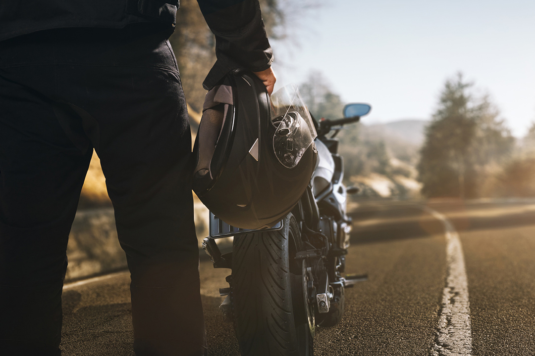 Motorcycle rider standing on the road next to his bike