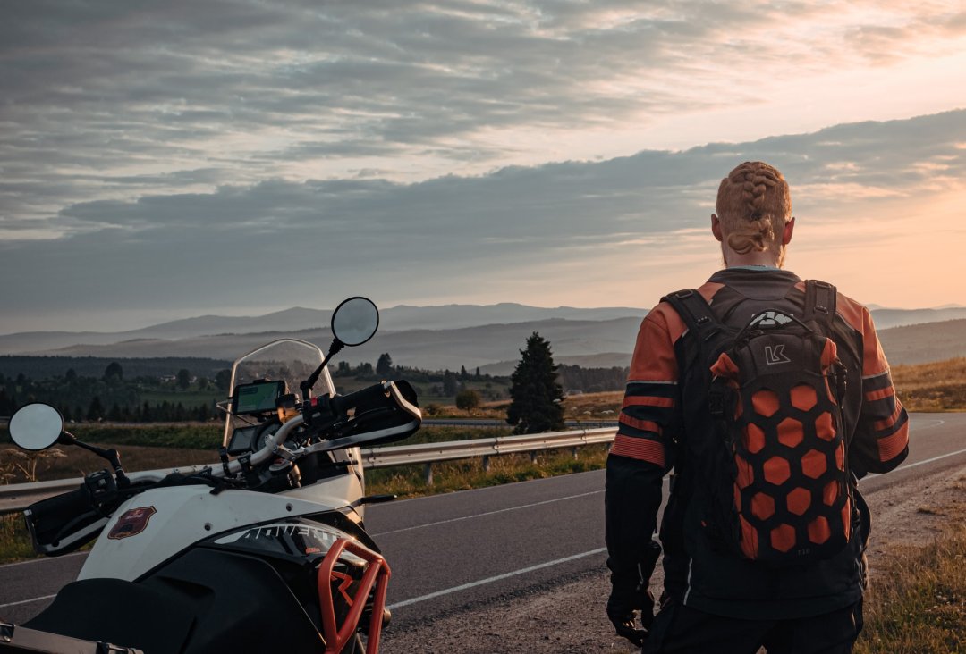 Homme debout à côté d’une moto en pleine nature - roadtrip moto