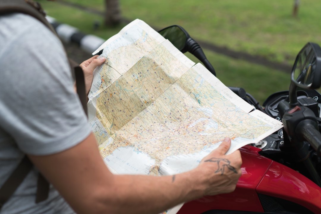 Homme tenant une carte routière à côté de sa moto - roadtrip moto